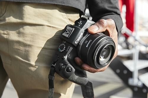 Person holding a Canon camera by their side